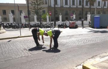 Dos operarios toman medidas en la calzada donde se implantará el nuevo tramo de asfaltado mixto