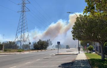 Varios camiones autobombas de bomberos tratan de apagar las llamas avivadas por las rachas del levante