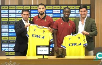 Ambos jugadores posan con la elástica amarilla junto a los responsables de la Dirección Deportiva