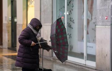 Una mujer intenta maniobrar con su paraguas ante los efectos de un vendaval en plena borrasca