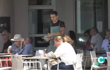 Un camarero sirve una mesa en una terraza de Cádiz. 