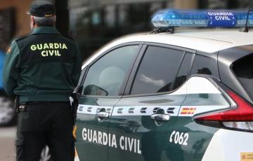 Un agente de la Guardia Civil junto a su vehículo de servicio