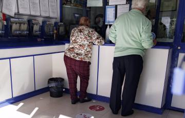 Dos clientes comprando lotería en una Administración.