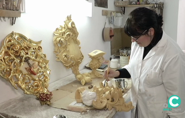 Una trabajadora interviene con un pincel una pieza en un taller de arte sacro.