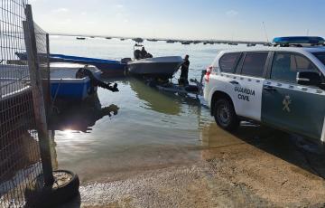 Un vehículo de la Guardia Civil saca del agua una de las embarcaciones