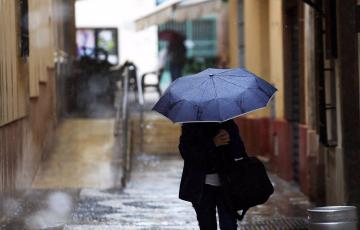 Una persona se protege de la lluvia en plena calle