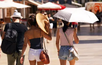 Viandantes se resguardan del calor de estos días. 
