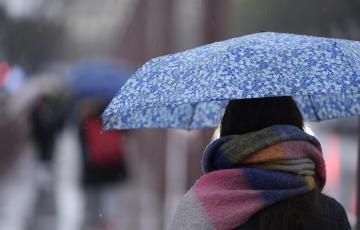 Una persona se protege de la lluvia con un paraguas Una persona se protege de la lluvia con un paraguas