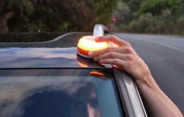 Una persona instala la baliza V16 en la parte alta del vehículo. 