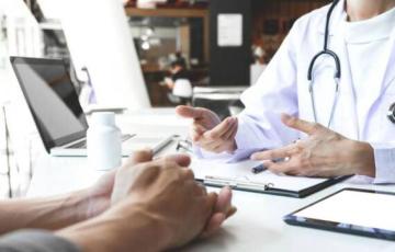 Un facultativo médico atiende a un paciente en consulta. 