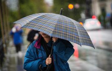 Una mujer intenta protegerse del mal tiempo con un paraguas