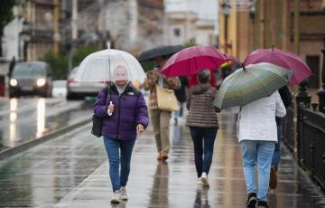Imagen de archivo de viandantes protegiéndose de la lluvia en Sevilla.