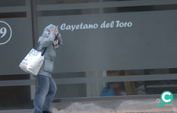 Una mujer se protege del fuerto viento en la mañana de este miércoles en la capital gaditana