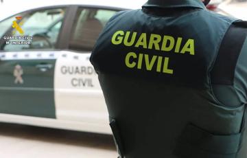 Un agente de la Guardia Civil junto a un vehículo oficial.
