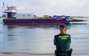 Un agente de la Guardia Civil frente a una barcaza para cruzar el río Guadalquivir camino del Coto de Doñana