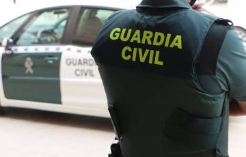 Un agente de la Guardia Civil junto a un vehículo oficial