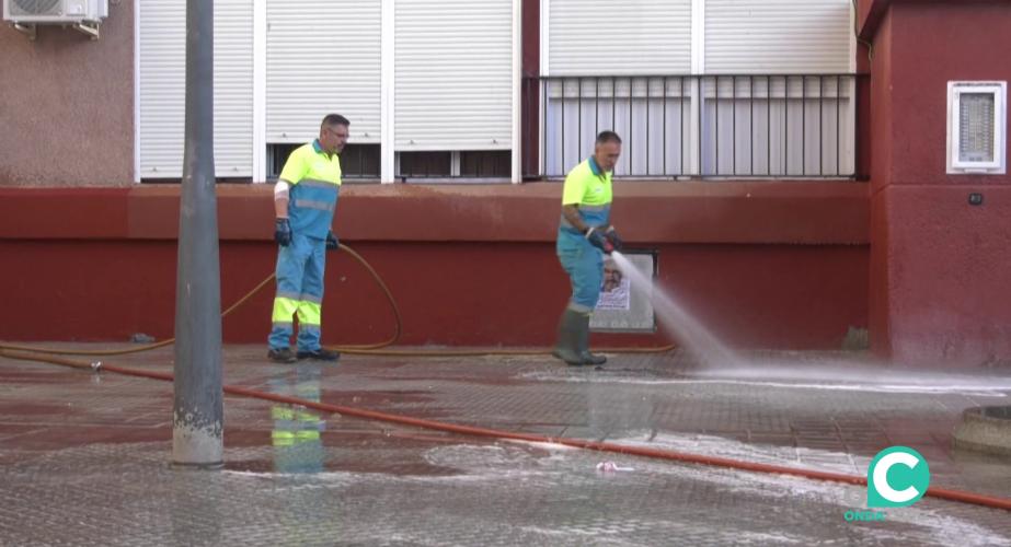 Dos operarios limpian el acerado bajo presión de agua