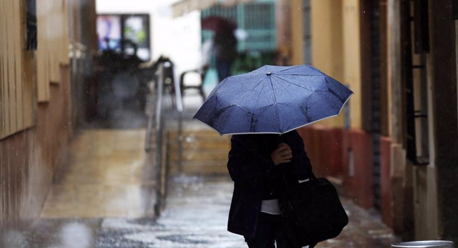 Una persona se protege de la lluvia en plena calle