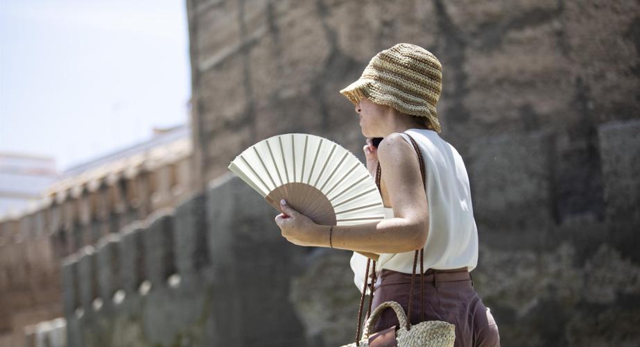 Una mujer se protege de las altas temperaturas con sombrero y abanico.