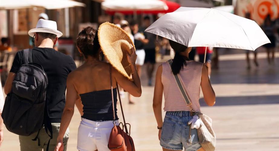Viandantes se resguardan del calor de estos días. 