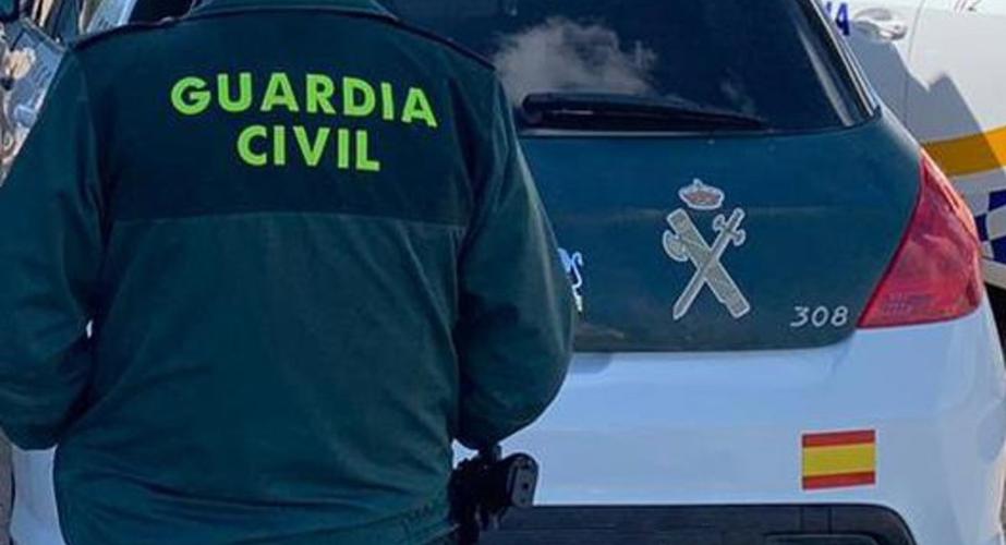 Un agente de la Guardia Civil junto a un vehículo oficial.