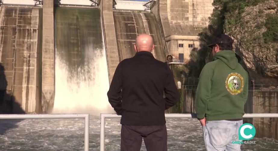Dos hombres observan el desembalse de agua en el pantano de los Hurones