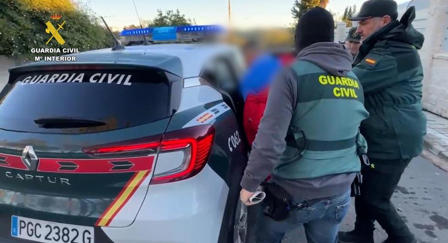 Agentes de la Guardia Civil introducen en el coche a uno de los arrestados