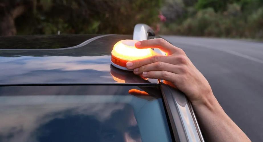 Una persona instala la baliza V16 en la parte alta del vehículo. 