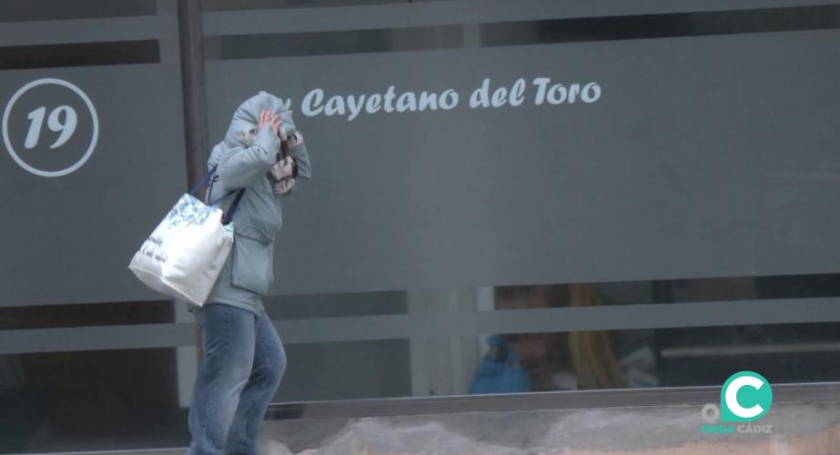 Una mujer se protege del fuerto viento en la mañana de este miércoles en la capital gaditana