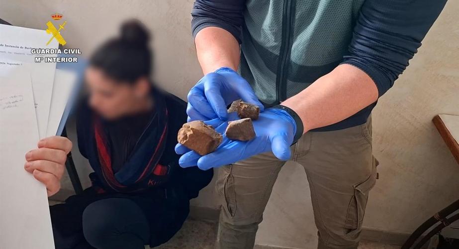 Un agente muestra un trozo de hachís incautado en un punto de venta de droga desarticulado en Barbate.