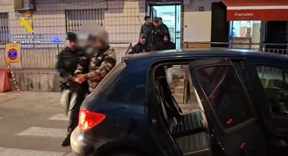 Agentes escoltan a uno de los arrestados en el operativo