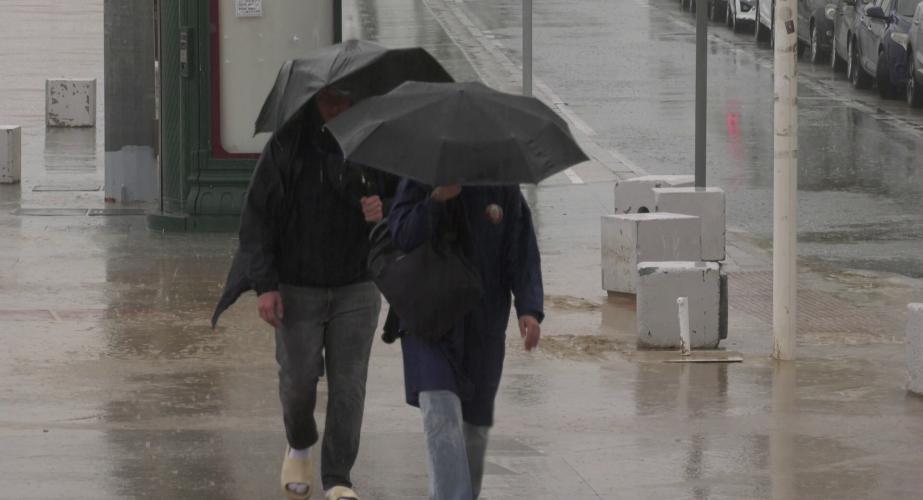 Dos viandantes con paraguas por el Paseo Marítimo de al capital gaditana en una imagen de archivo