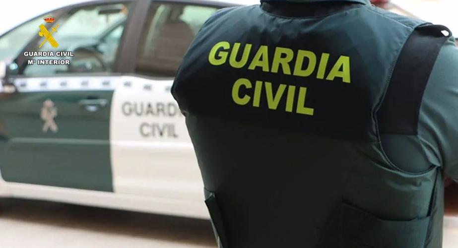 Un agente de la Guardia Civil junto a un vehículo oficial.