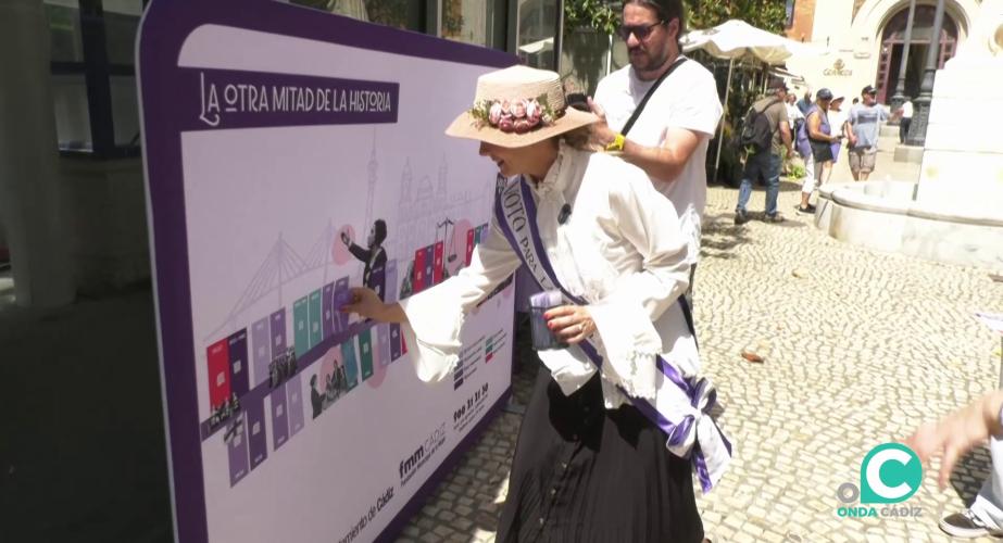 Una sufragista marca el mural de línea de tiempo instalado en la capital gaditana.