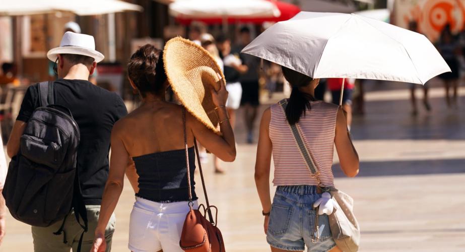 Viandantes se protegen en la calle de las altas temperaturas