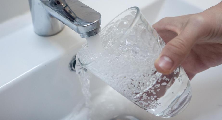 Una persona llena un vaso de agua de un grifo