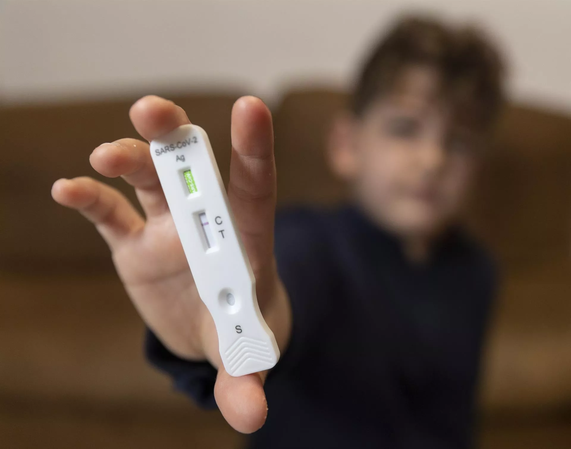 Un niño enseña un test de antígenos Un niño enseña un test de antígenos