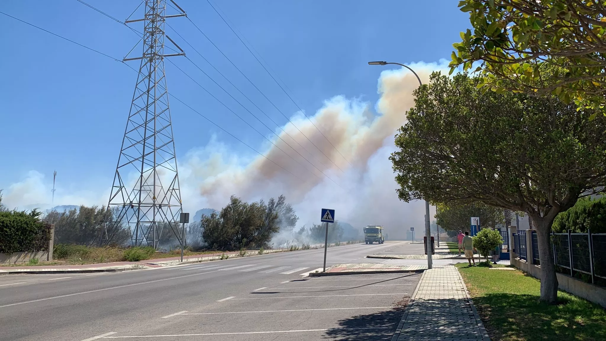 Varios camiones autobombas de bomberos tratan de apagar las llamas avivadas por las rachas del levante