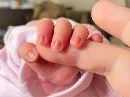 Un bebé recién nacido coge el dedo a su madre