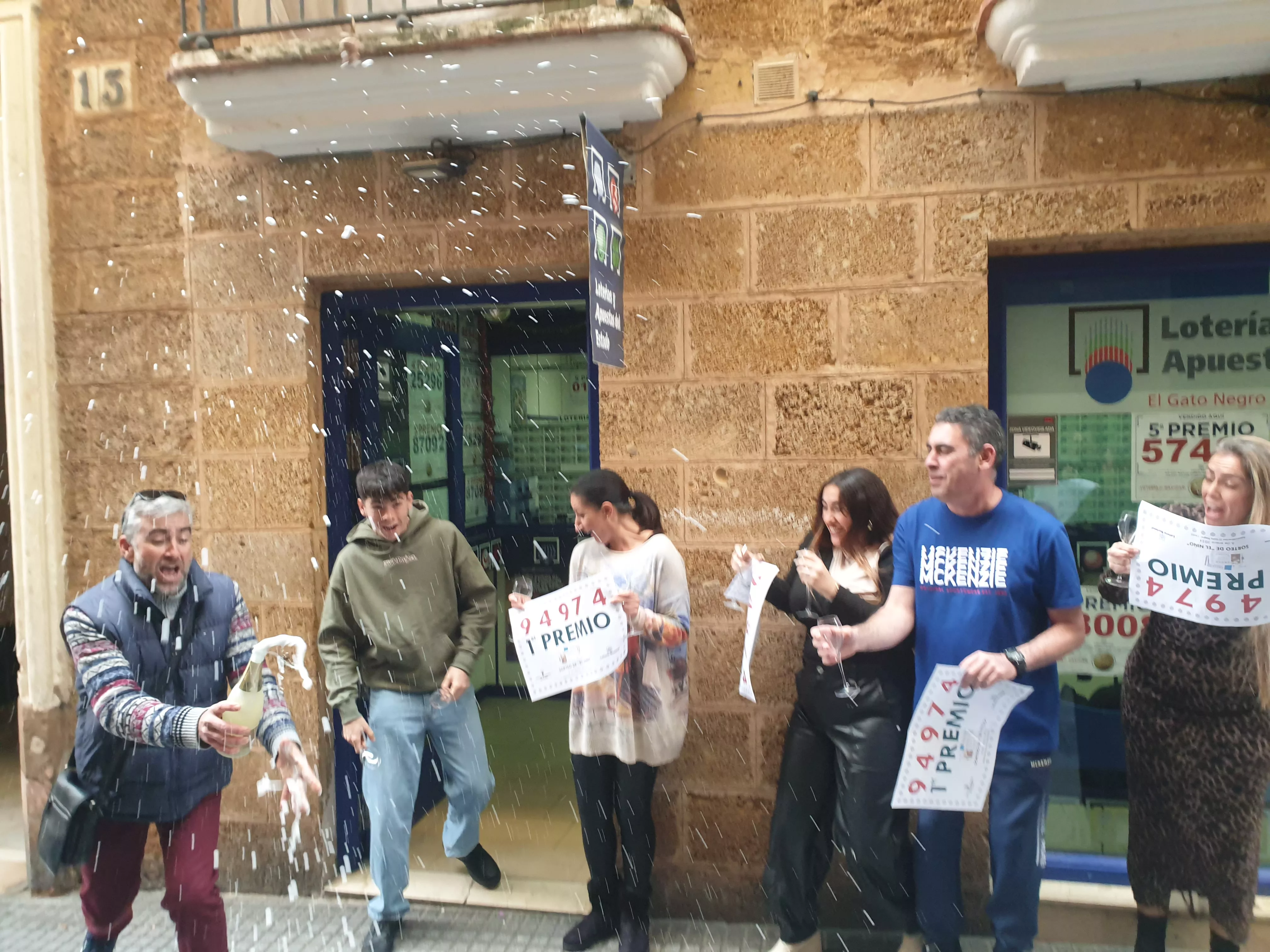 Los propietarios de la administración número 3 de la calle José del Toro descorchando una botella de champán.