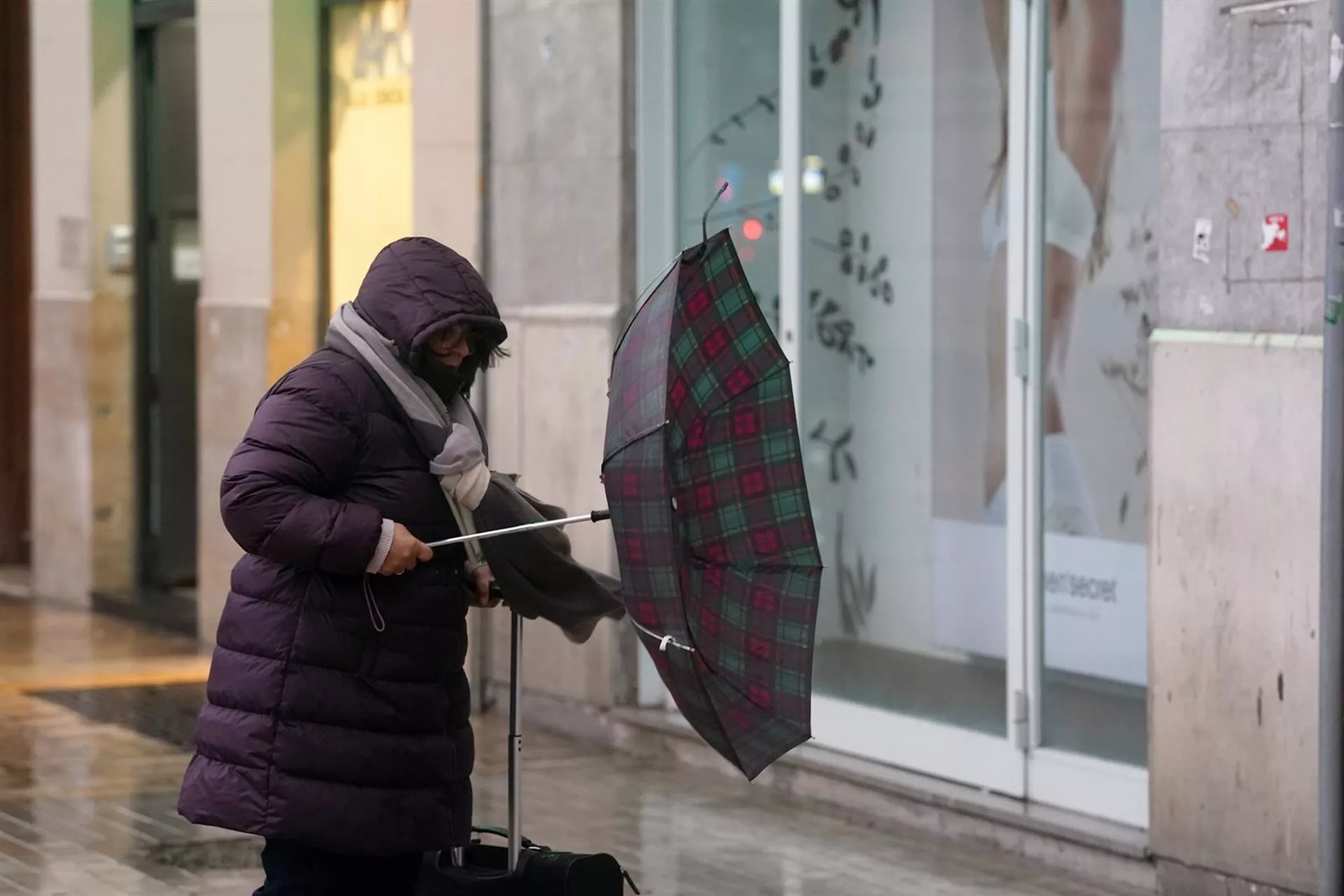 Una mujer intenta maniobrar con su paraguas ante los efectos de un vendaval en plena borrasca