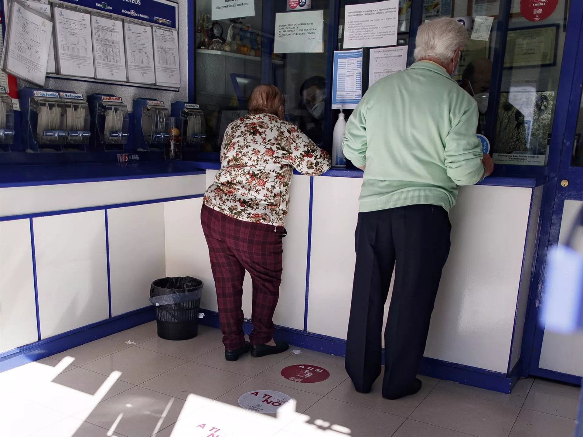 Dos clientes comprando lotería en una Administración.