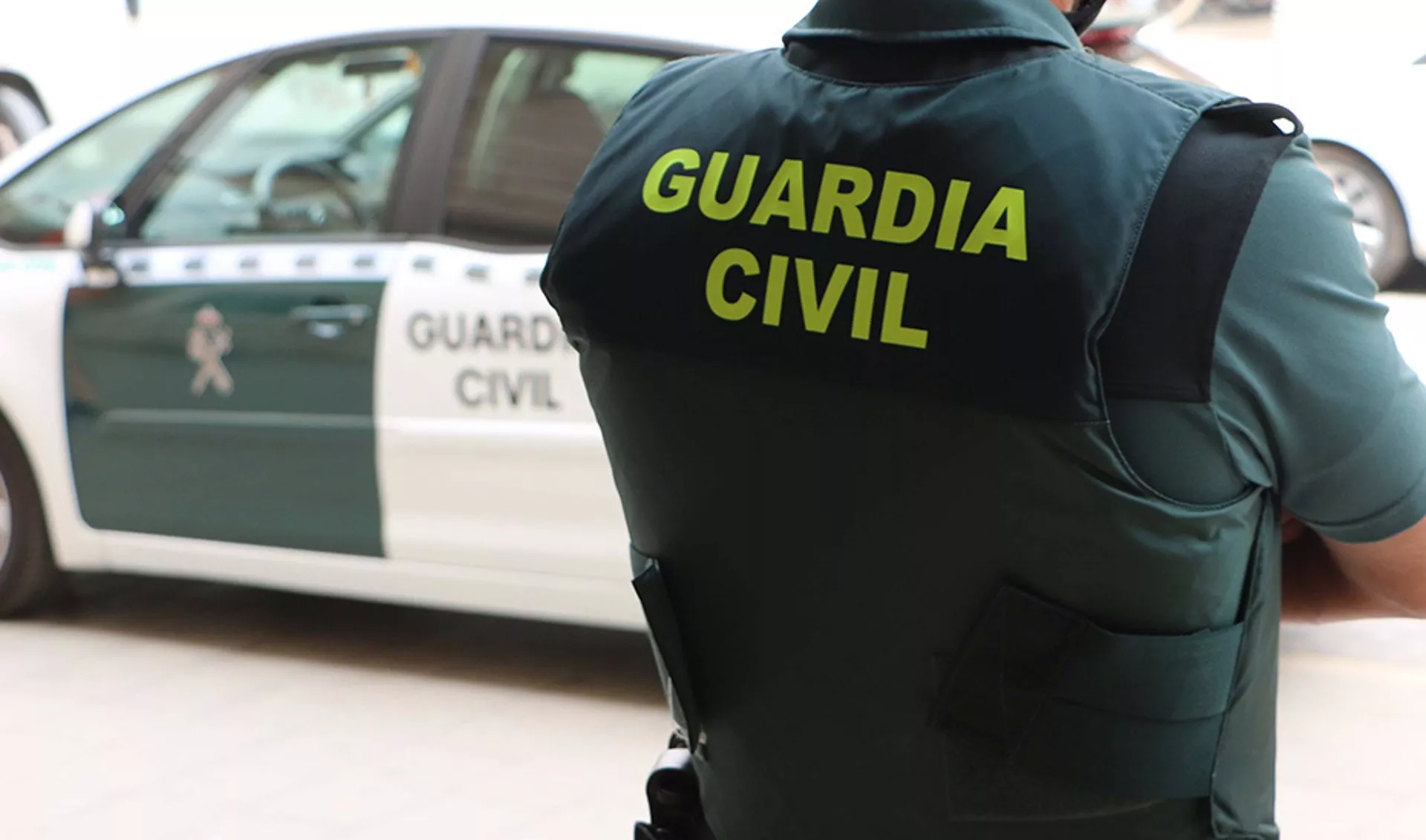 Un agente de la Guardia Civil, de espaldas, junto a un vehículo oficial en una imagen de archivo.