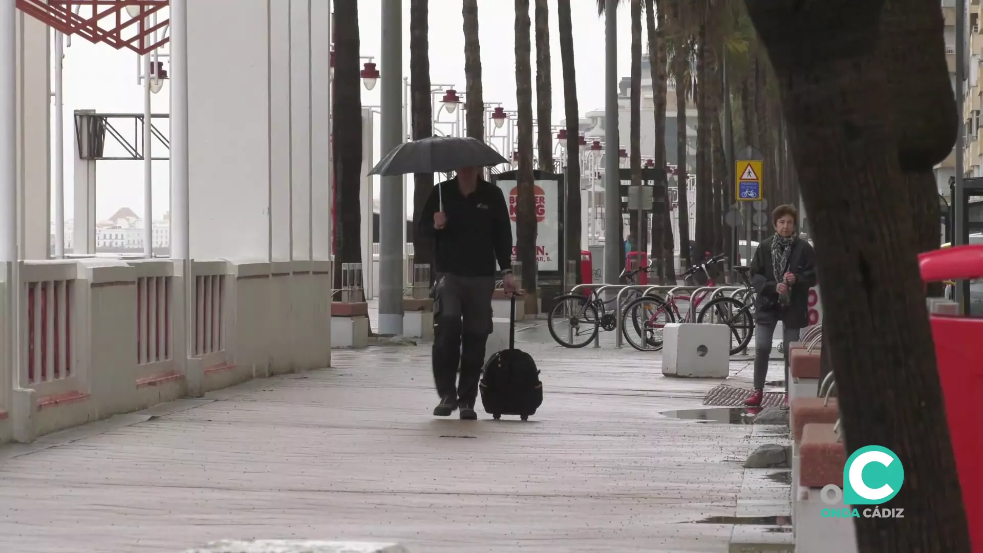 Un viandante se resguarda de la lluvia en Cádiz. 