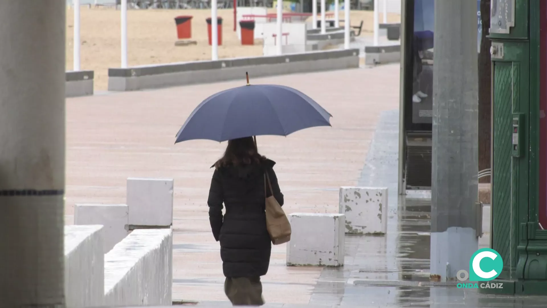 Una mujer camina protegida con un paraguas por el Paseo Maritimo de la capital gaditana