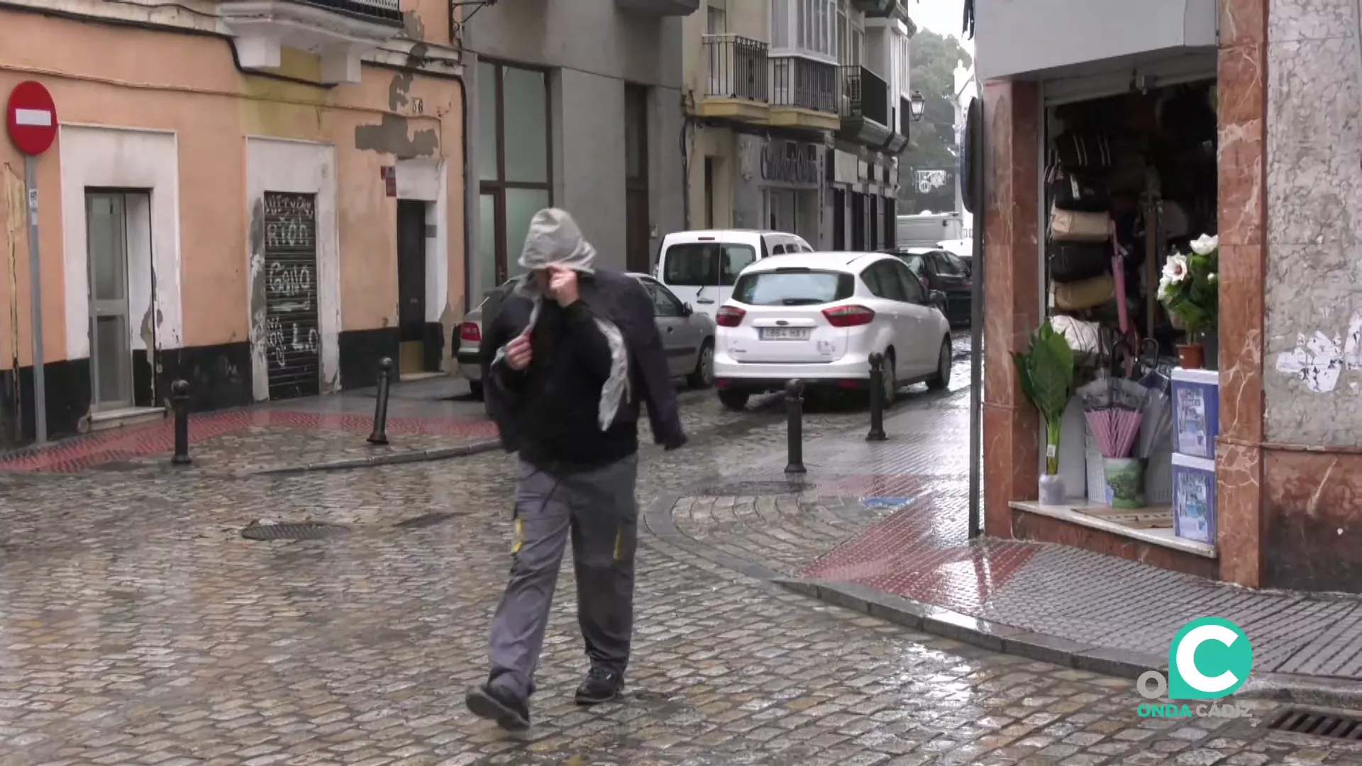 Un viandante se refugia de las inclemencias en la calle La Rosa