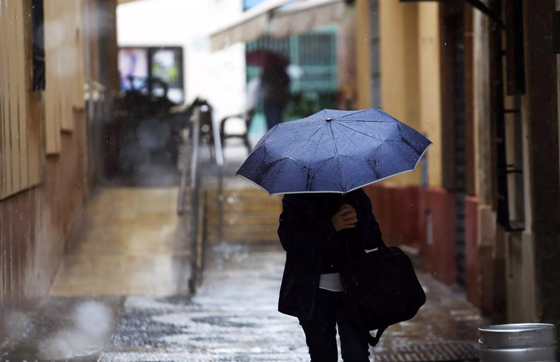 Una persona se protege de la lluvia en una imagen de archivo. Una persona se protege de la lluvia en una imagen de archivo.