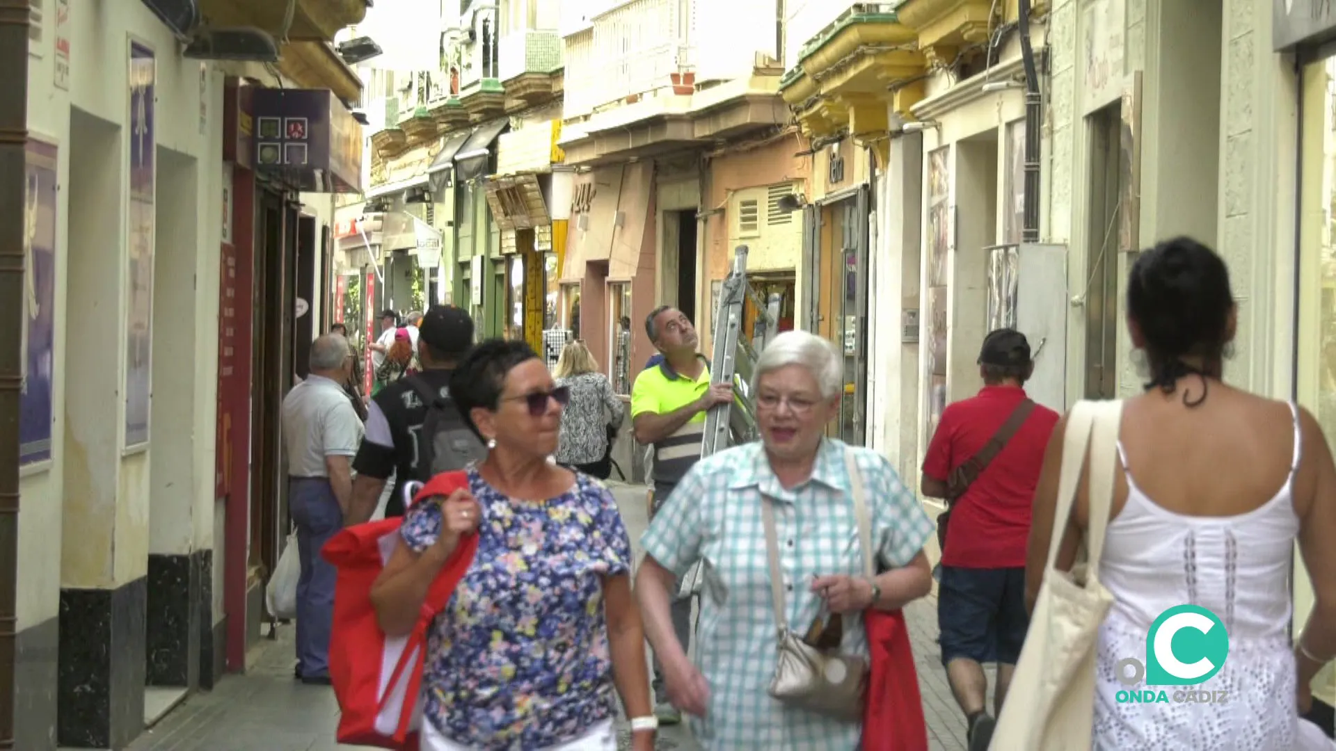 VIandantes por una calle de establecimientos comerciales por el centro de la ciudad