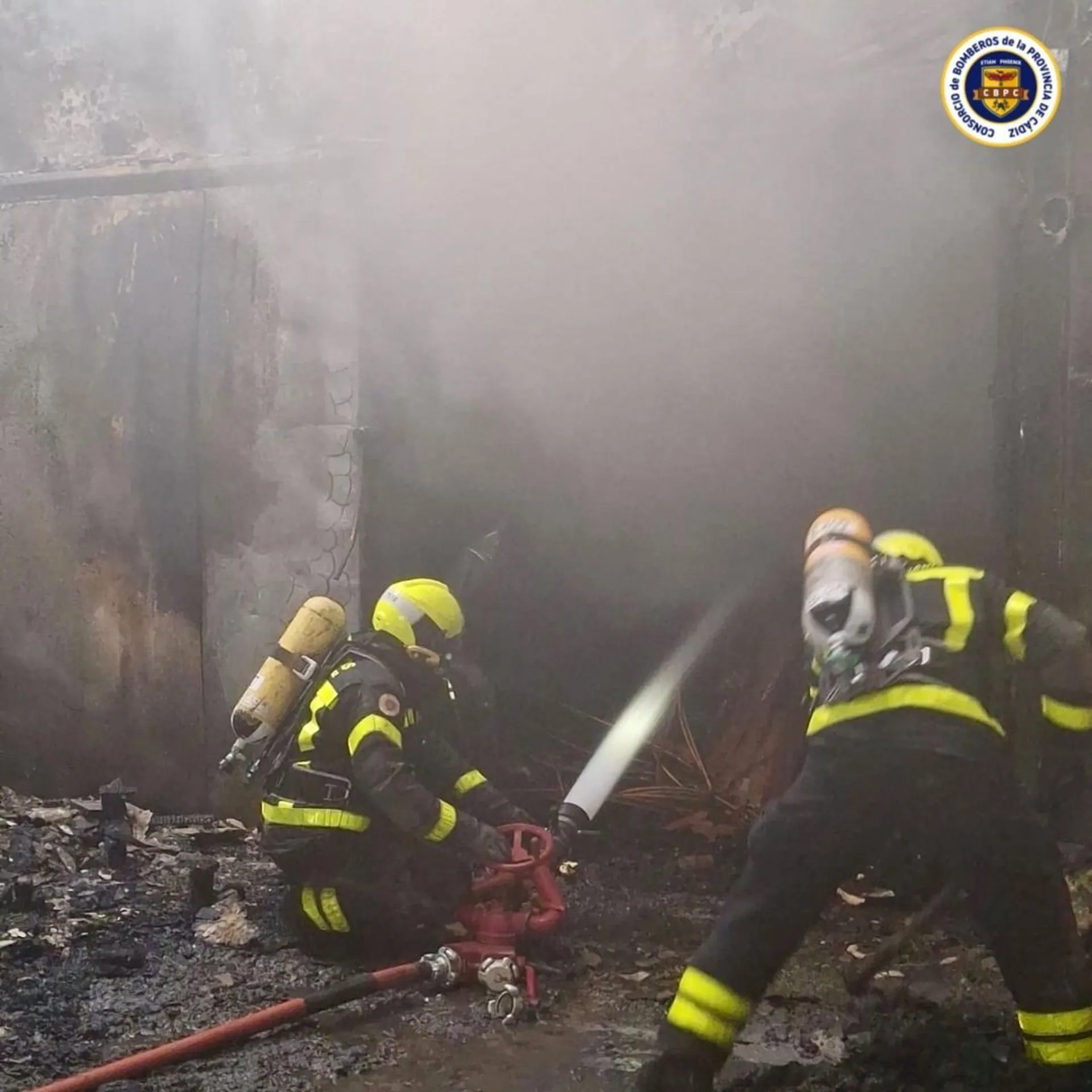 Dos bomberos actuando en el incendio en una fábrica de conservas de Tarifa.
