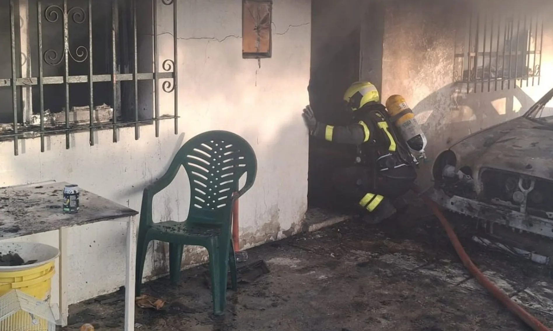 Un bombero actuando en la entrada del inmueble donde se produjo el siniestro Un bombero actuando en la entrada del inmueble donde se produjo el siniestro